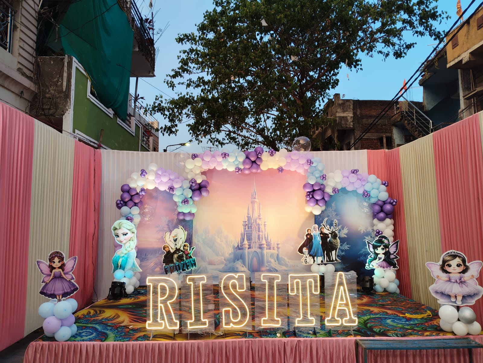 Princess-castle themed birthday stage with fairy-tale cutouts and a lit RISITA name sign