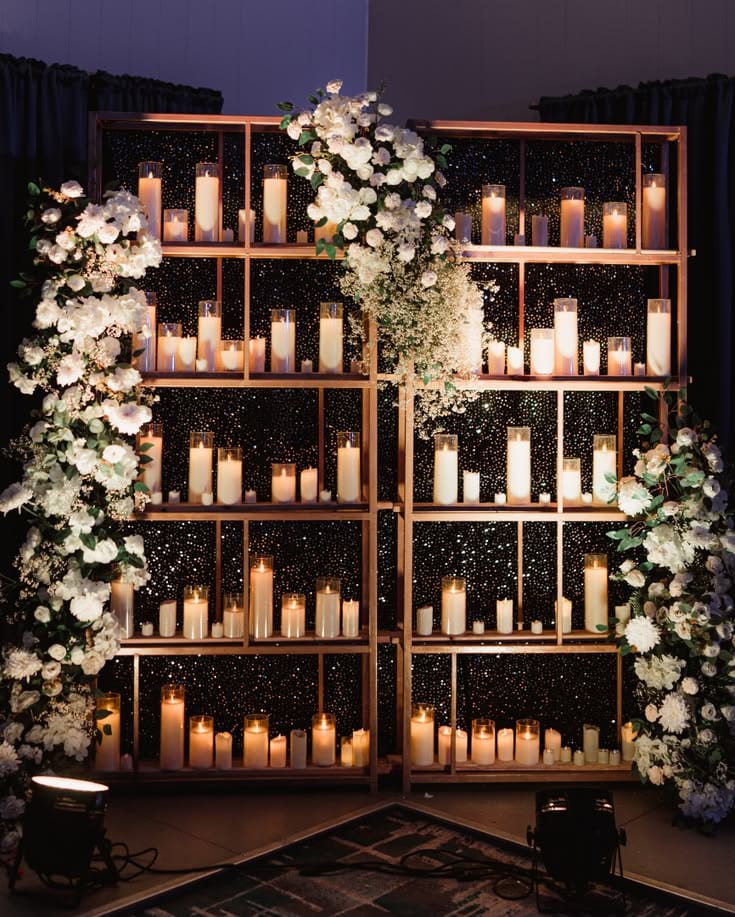 Wooden display shelves filled with candles and framed by cascading white flowers
