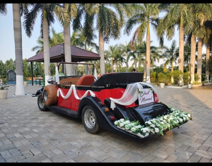 Red vintage car adorned with floral garlands for the baraat