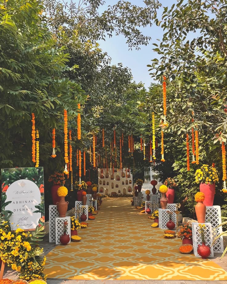 Outdoor celebration walkway with hanging marigold strings, yellow flowers and red-yellow accents