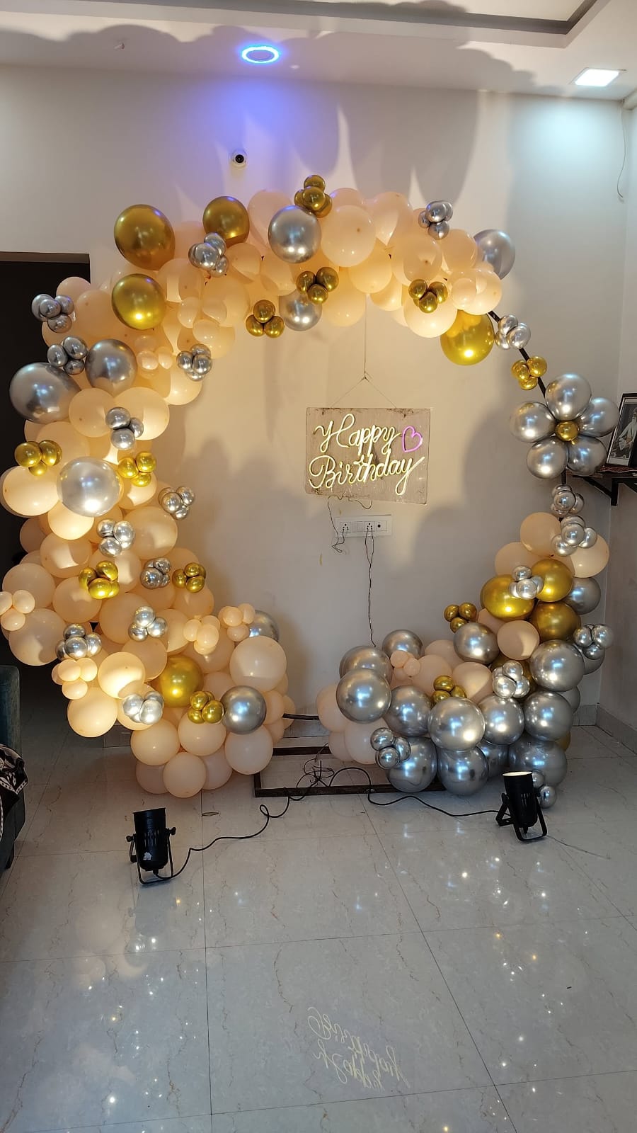 Ring of gold, silver and cream balloons around a Happy Birthday backdrop