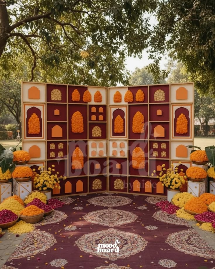 Colourful arched niche backdrop with marigolds, cushions and patterned rugs for a pre-wedding celebration