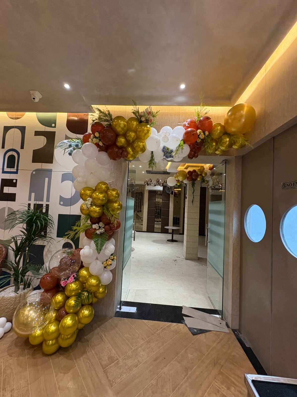 Entrance doorway wrapped in gold, green and white balloon garlands