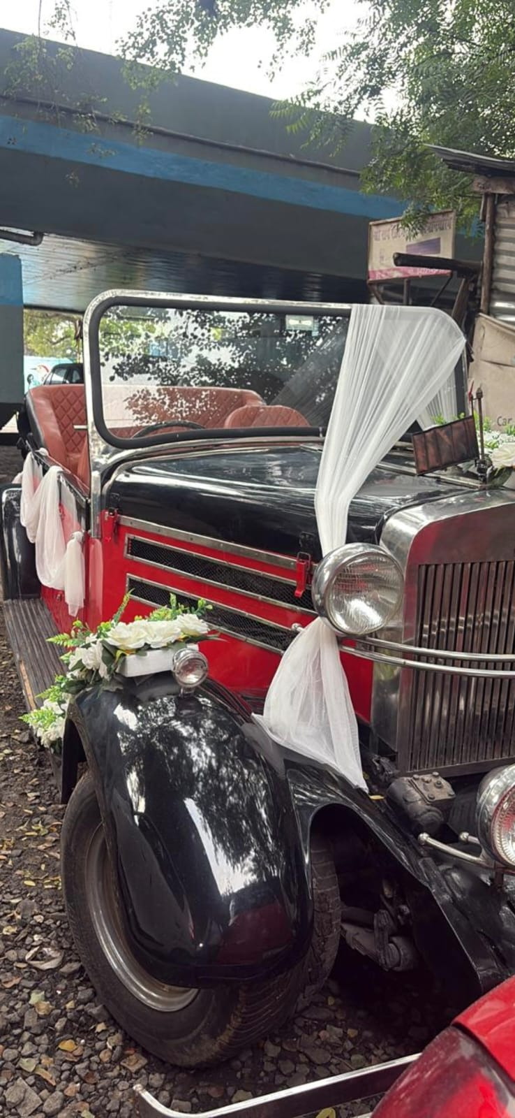 Black vintage car with white flowers and a draped bow on its bonnet