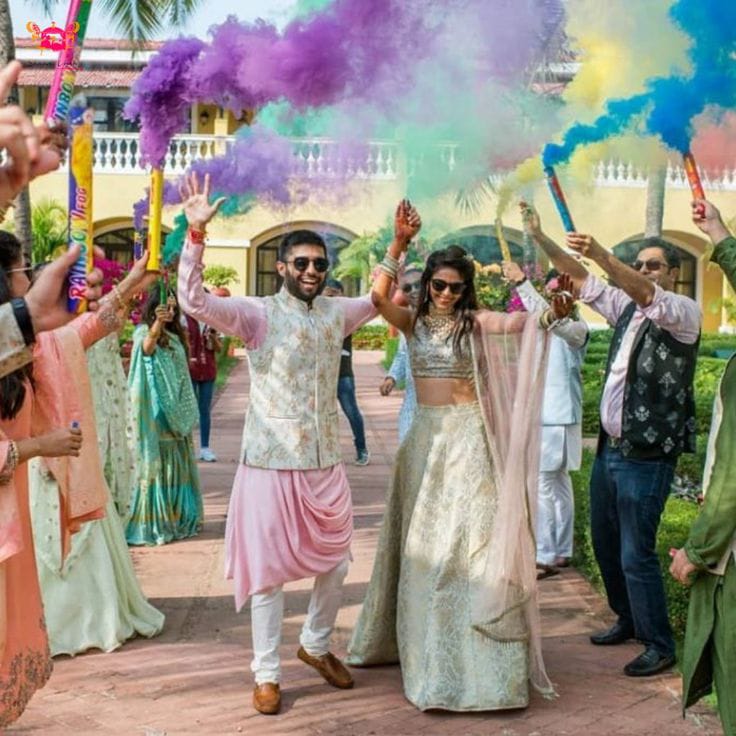Wedding couple and guests celebrating beneath purple, blue and yellow colour smoke