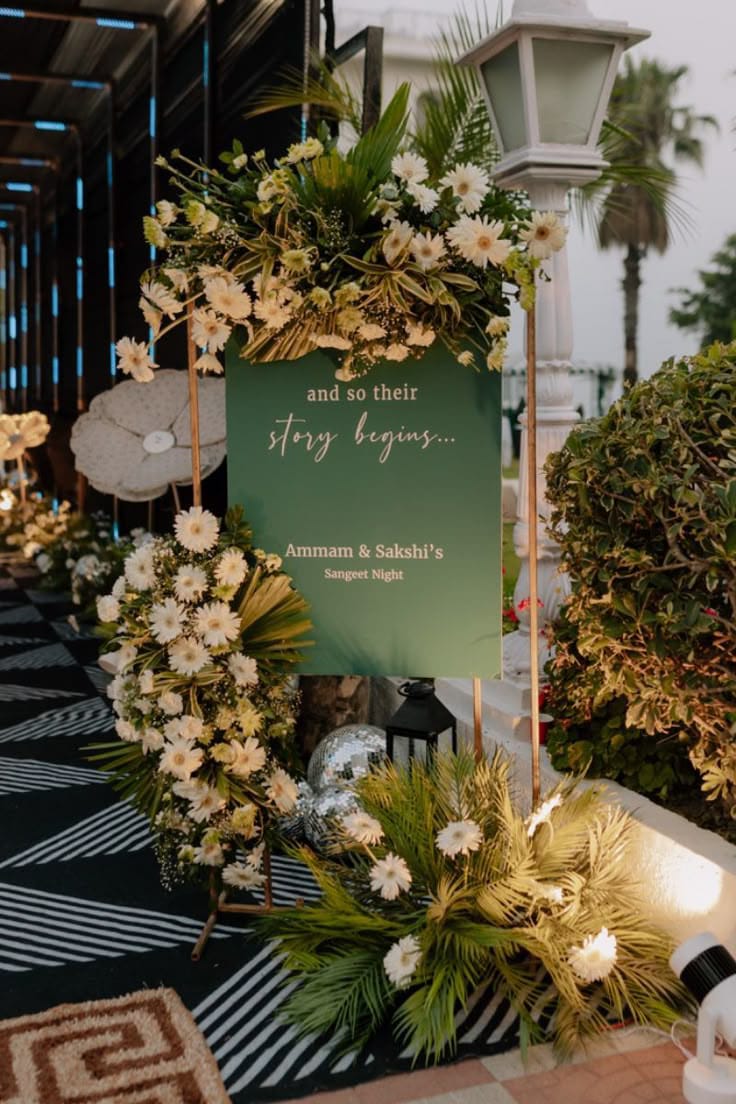 Green wedding welcome sign framed with white-yellow flowers, foliage and pampas grass