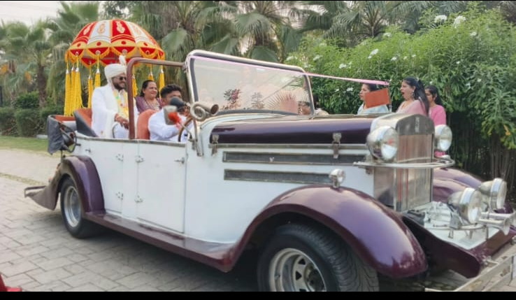 Vintage car decorated in red and white carrying the bride