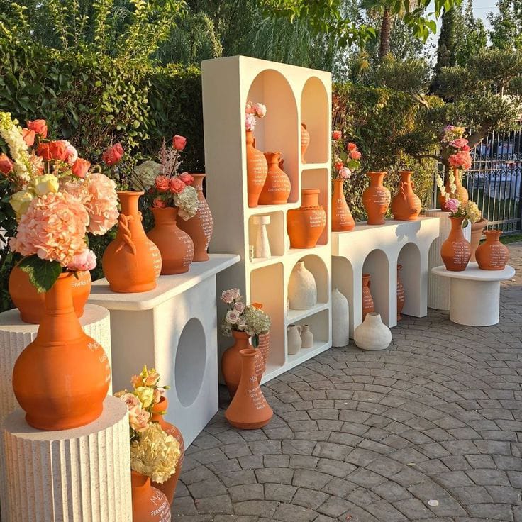 White arched shelving styled with terracotta pots and peach floral arrangements