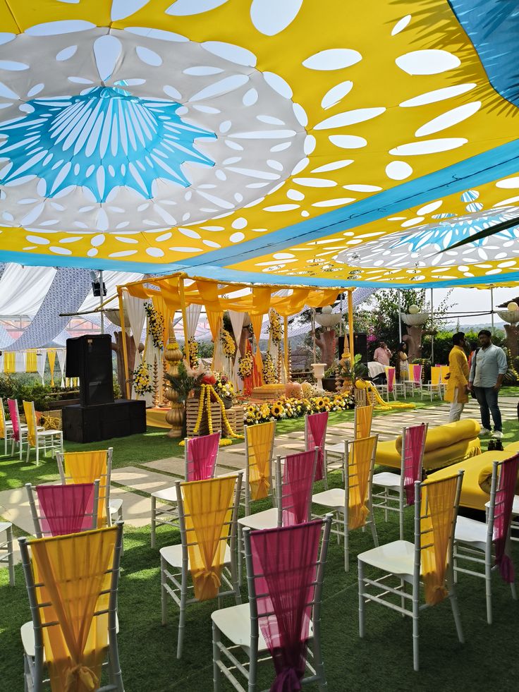 Colourful outdoor celebration seating beneath a yellow and blue patterned canopy