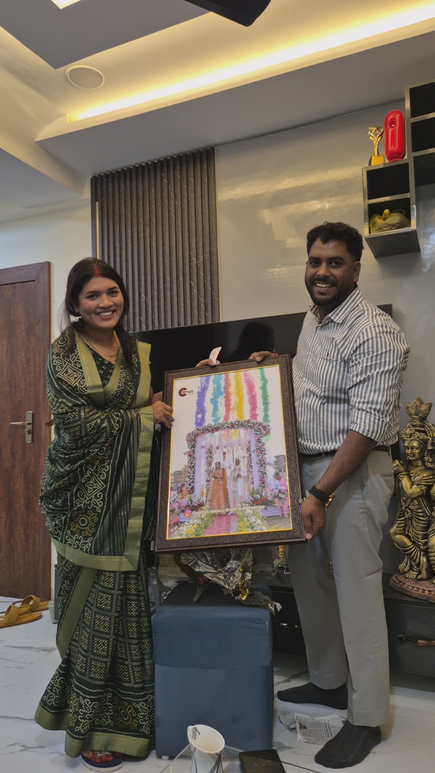 Two people holding a framed photograph of a Creative World floral wedding setup with colour smoke
